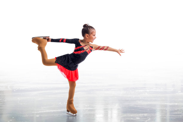 小溜冰者摆在红和黑的衣服在冰上孤立在白色的背景图片下载