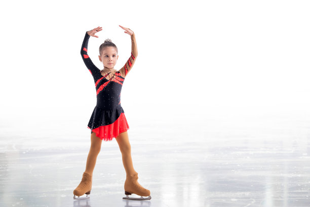 小溜冰者摆在红和黑的衣服在冰上孤立在白色的背景图片下载