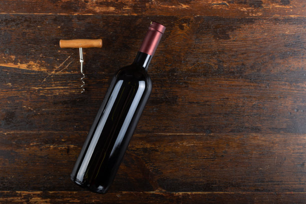 红酒瓶和开塞钻在木制背景上。酒精饮料。前视图。图片下载