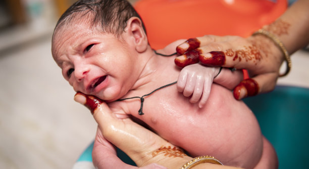 无法辨认的母亲正在给她的新生儿洗澡。图片下载