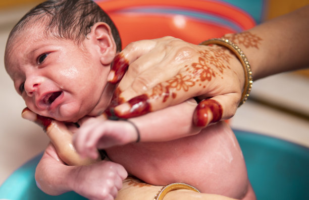 无法辨认的母亲正在给她的新生儿洗澡。图片下载