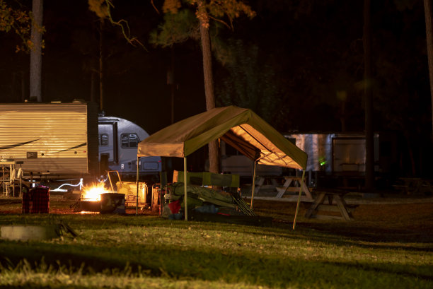 夜间拍摄的房车露营在松林与营火照亮周围的余烬留下的痕迹图片下载
