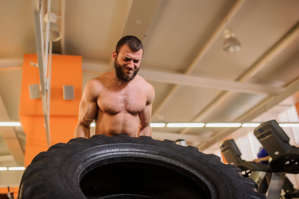 有胡子的男人在健身房翻转沉重的轮胎图片下载