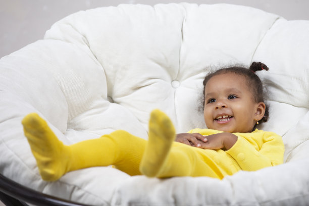 一个顽皮的非洲裔美国小女孩躺在安乐椅上。图片下载