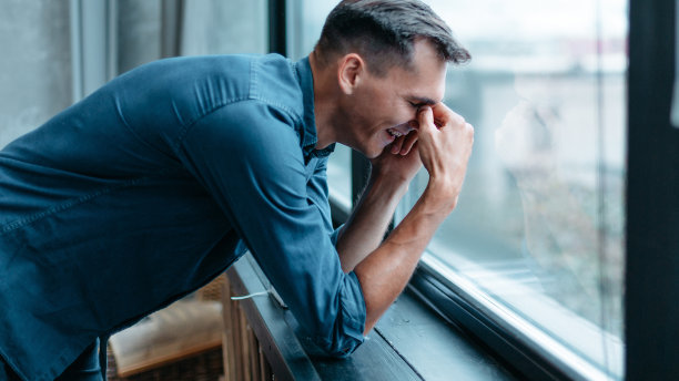 一个微笑的男人站在窗边用智能手机说话图片下载