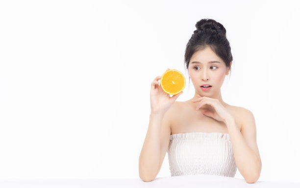 年轻的美丽女孩展示橙子切片维生素C为好皮肤肖像美丽漂亮的年轻亚洲女人孤立在白色的背景年轻女士惊喜的脸和幸福吃水果得到好的皮肤图片下载