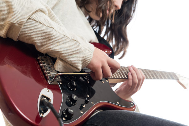 一个年轻人一边弹吉他一边练习他的音乐学习。图片下载