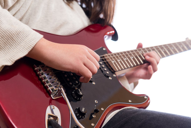 一个年轻的吉他手的手拨弄着她的吉他弦。图片下载