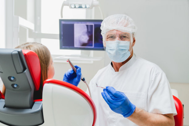 成功的男正畸牙医治疗手术病人，龋齿，龋齿，制作单板，填补牙齿看着相机。口腔学的概念图片下载