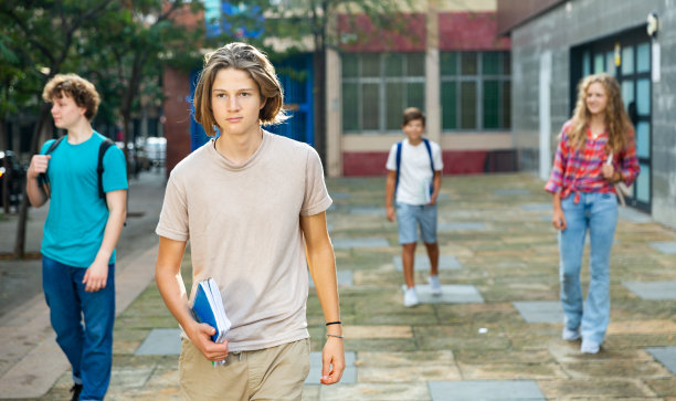 一个少年在完成大学课程后走在夏天的街道上图片下载