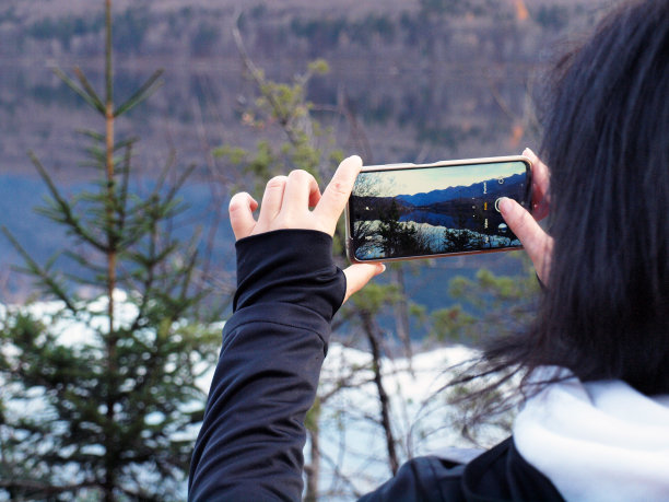 一个斯洛文尼亚徒步旅行者在冬天日落后用智能手机拍摄博欣吉湖的照片图片下载
