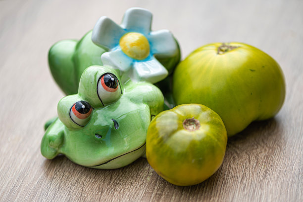 新鲜美味的绿色西红柿和木制桌子上的绿色陶瓷青蛙，特写图片下载