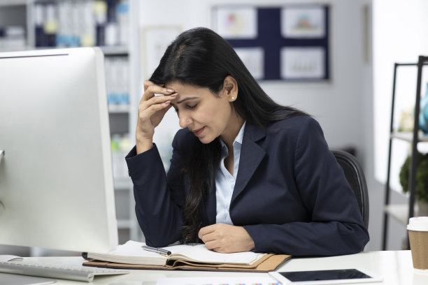 女商人坐在室内办公室的桌子前工作。库存图片图片下载