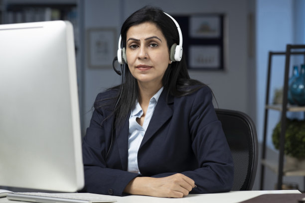 迷人的女商人坐在室内办公室的桌子上，工作。库存图片图片下载