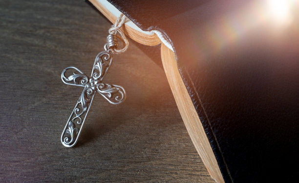 古老的木桌上放着美丽的基督教十字架和一本祈祷书。图片下载