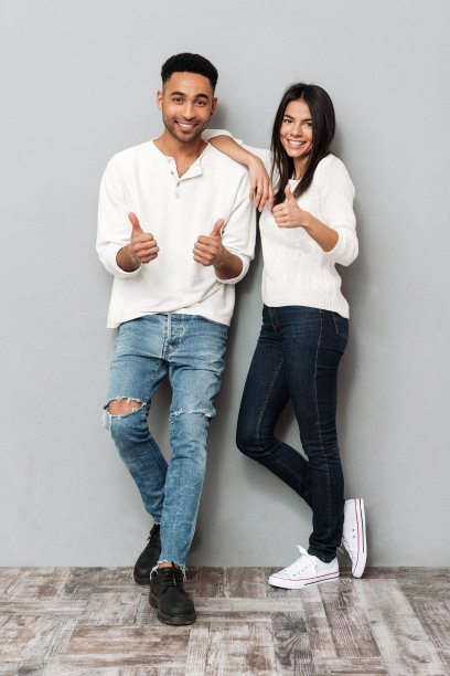 一对幸福的年轻情侣站在灰色的墙外图片下载