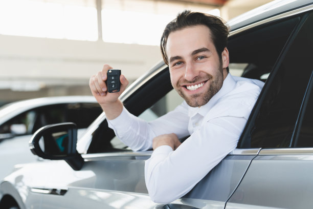 新的幸运车主。高加索英俊的男子商人购买新车汽车，持有汽车钥匙坐在汽车内的经销商商店。图片下载