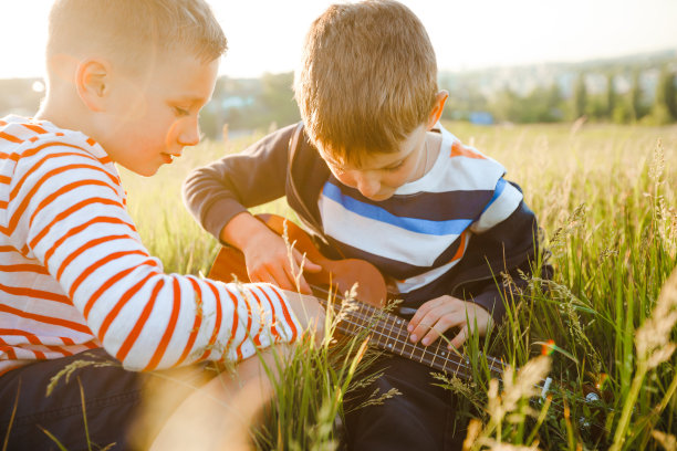 学龄男孩学习弹尤克里里琴。图片下载