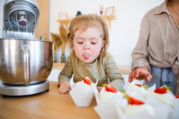 妈妈和女儿正在用奶油烤一道漂亮的甜点。图片下载