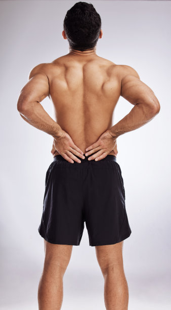 在摄影棚背景下，一个男人正在经历背部疼痛图片下载