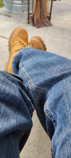 男人的双腿交叉在蓝色牛仔裤和靴子上图片下载