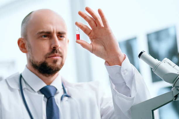 科学家拿着一安瓿疫苗坐在实验室的桌子前图片下载