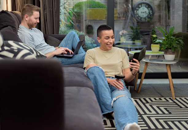 幸福的人夫妇网上购物的年轻人购买网店，企业家支付使用便携式设备，夫妇享受购买礼物坐在地板上与笔记本电脑和智能手机在家里。图片下载