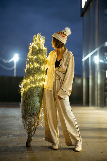 购物中心附近带着彩灯圣诞树的妇女图片下载