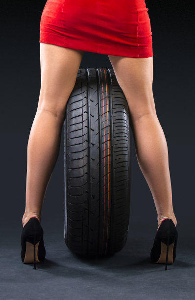 新的夏季轮胎和美丽的女性腿的女士穿着高跟鞋在黑暗的背景。垂直的摄影。图片下载