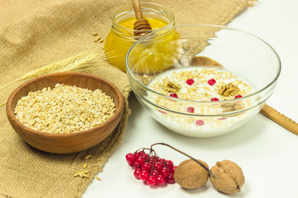 木碗里的生麦片片。大麦片粥加牛奶，蜂蜜，桂花和核桃。图片下载