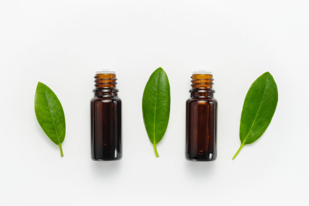 香精油瓶与植物叶子在白色的背景图片下载