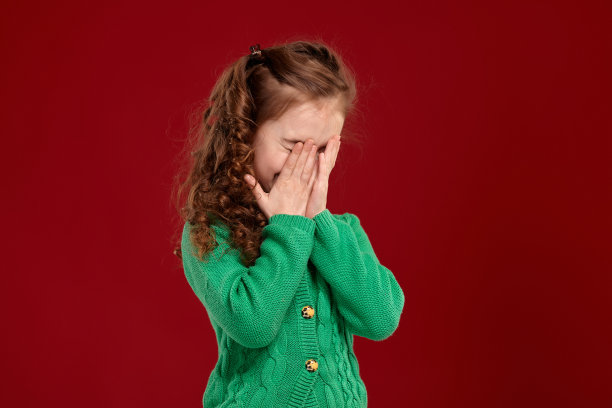 一个长着一头卷发的黑发小女孩的肖像，在红色的背景下摆姿势图片下载