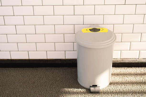 对着垃圾桶的面具。扔掉用过的口罩。装有医疗废物的垃圾桶。图片下载