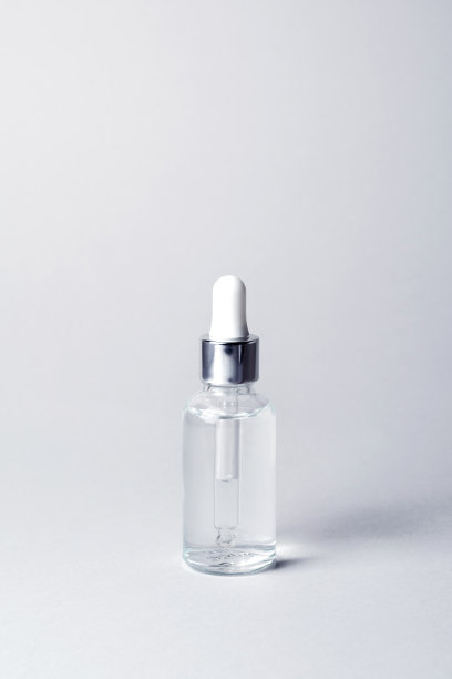 透明玻璃瓶与银色和白色的移液管在灰色背景模型。面部血清滴管瓶特写。化妆品品牌。最小的概念。垂直照片，复制空间图片下载