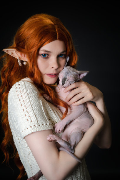 画像的小精灵cosplay年轻女子在白色连衣裙仔细拥抱睡着的斯芬克斯小猫图片下载