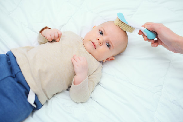 妈妈用白色背景的特殊梳子给宝宝梳头图片下载