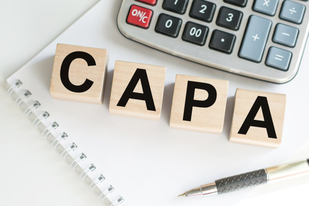 卡帕。有字母的木块放在桌子上，旁边是计算器和钢笔和笔记本。经营理念的形象。图片下载