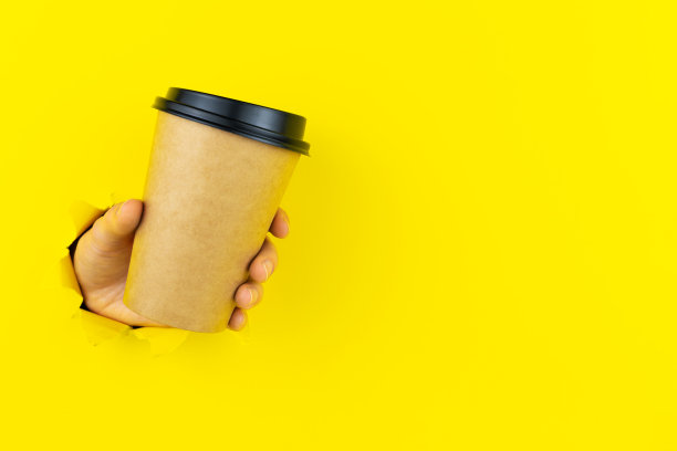 一只手拿着破洞里的纸制咖啡杯图片下载