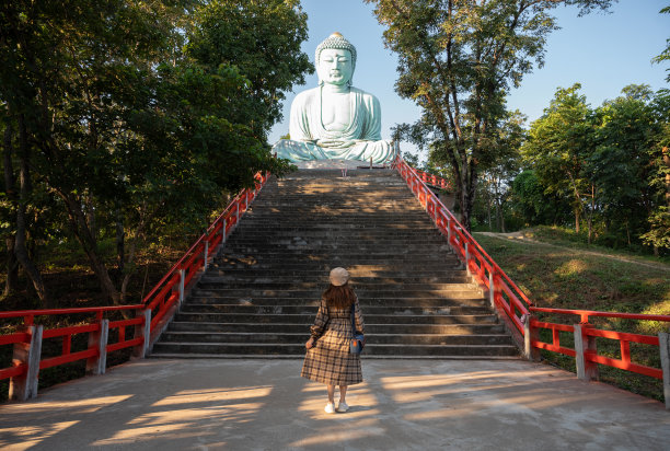 在泰国兰邦省美他区宁静的山顶上，一名女游客站在大佛模型前。图片下载