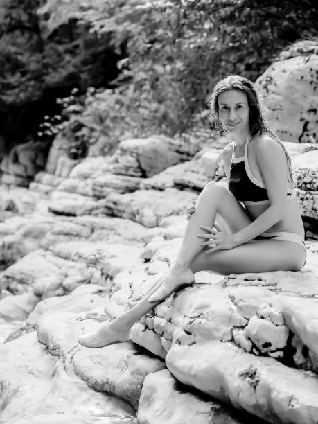 一个穿着比基尼的女孩坐在国家保护区的岩石海岸上。黑白照片。白色悬崖峡谷。户外活动图片下载