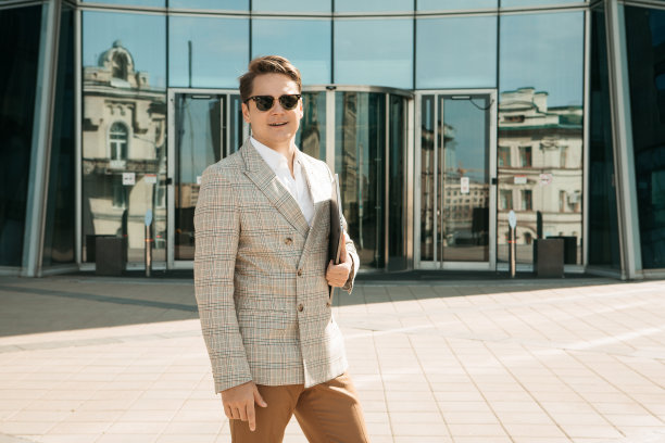 商业、人与成功理念:英俊微笑的年轻商人手持笔记本电脑图片下载