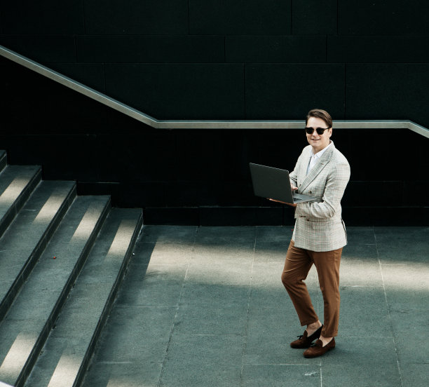 商业、人与成功理念:英俊微笑的年轻商人手持笔记本电脑图片下载