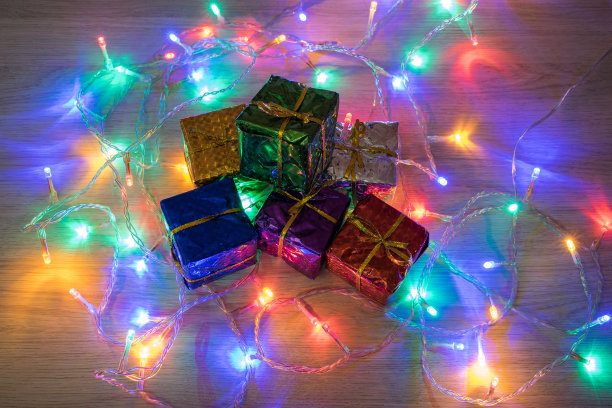 木制背景上有几个圣诞礼物盒和圣诞灯。圣诞装饰图片下载