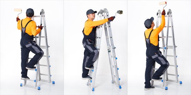 高级亚洲男子穿着橙色制服衬衫，帽子和手套，作为油漆工与金属高梯子图片下载