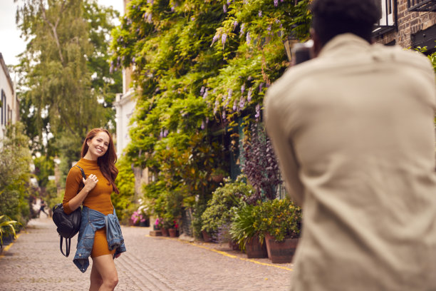 当年轻夫妇一起穿越城市时，一个女人摆着姿势，一个男人在相机上拍照图片下载