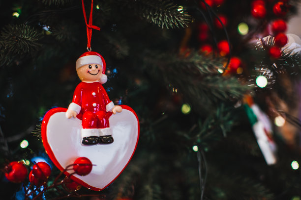 圣诞玩具小雕像，滑稽的小精灵戴着圣诞老人的帽子挂在圣诞树的树枝上。图片下载