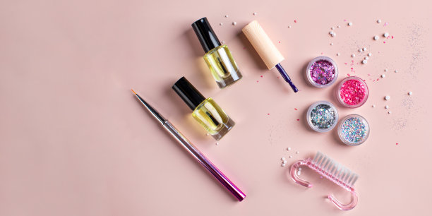 一套亮片，清漆，刷子在粉红色的背景上创造一个节日美甲。本空间图片下载