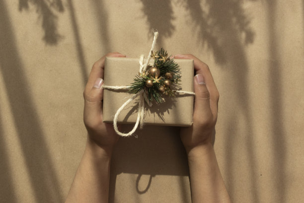 一个人的手，并分享一个礼品盒包装和装饰用丝带和蝴蝶结，在特殊的日期，工作室的礼物对象图片下载