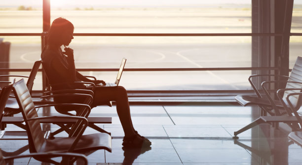 一个女人在机场用笔记本电脑工作。图片下载
