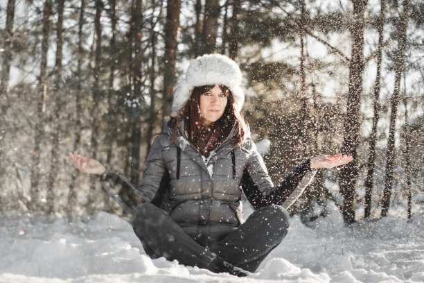 年轻女子在瑜伽姿势在雪地公园。图片下载